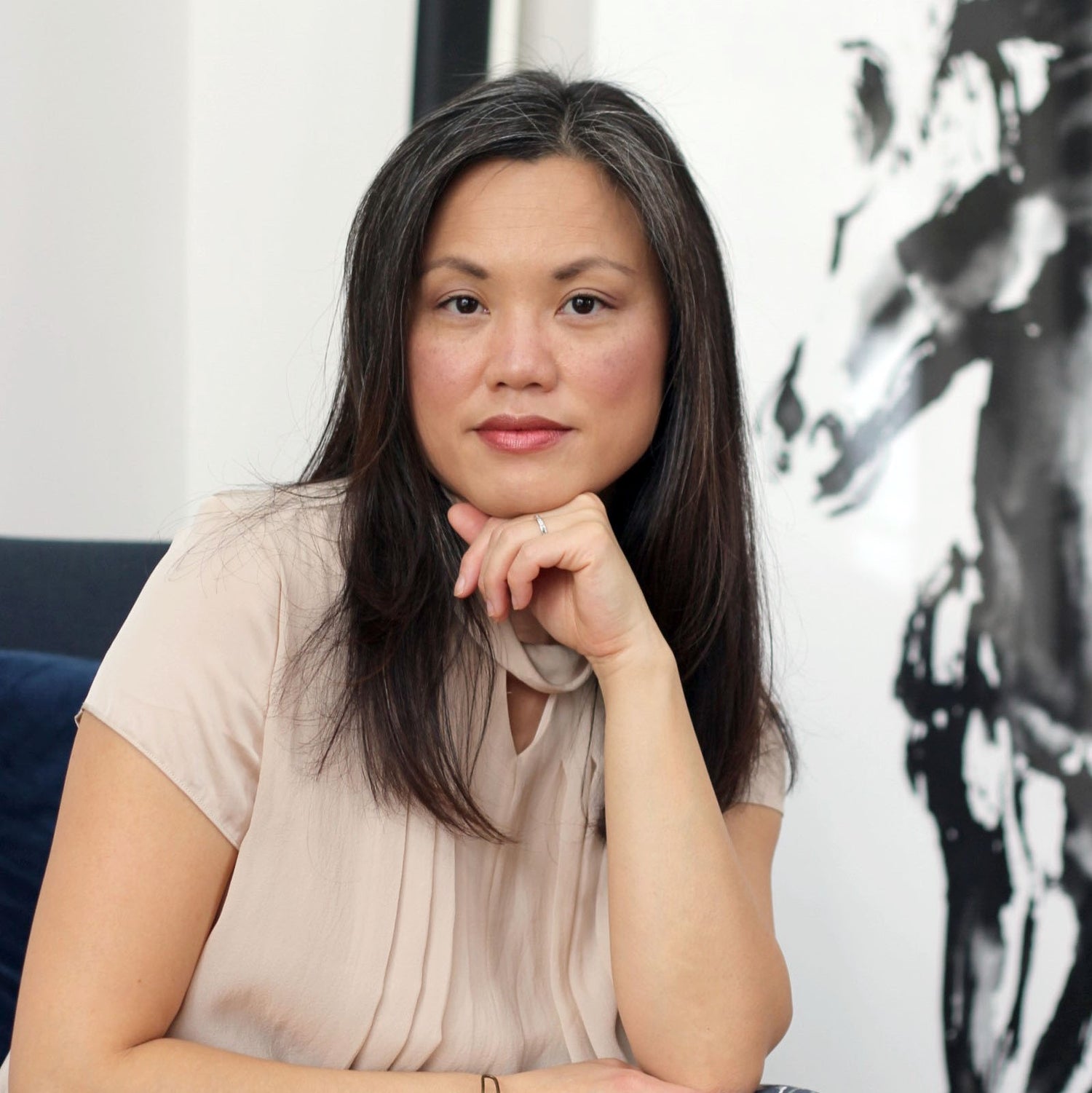 Leslie Tan, owner of Do Good Paper Co. online stationery company, posing for a portrait on a chair in front of a horse painting