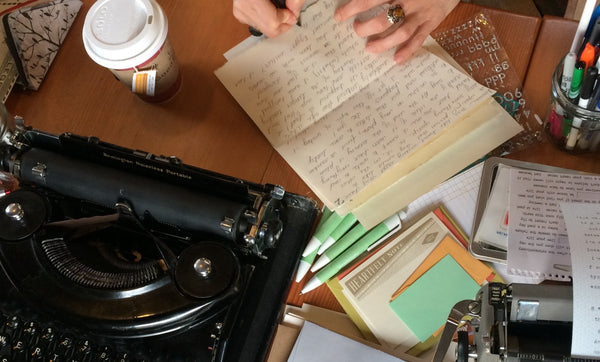 black typewriter, hand-written letter and other stationery supplies on a wooden table