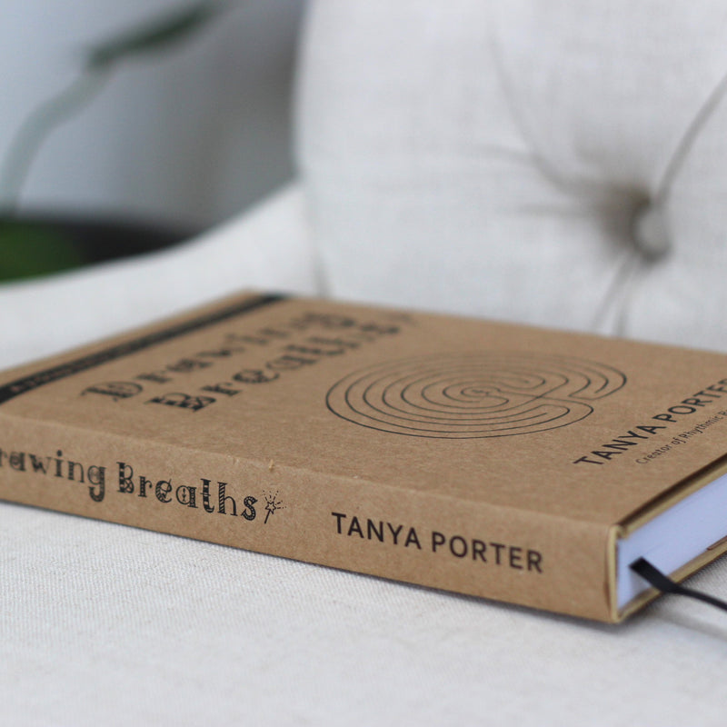 Drawing Breaths book by Tanya Porter lying flat on a beige chair