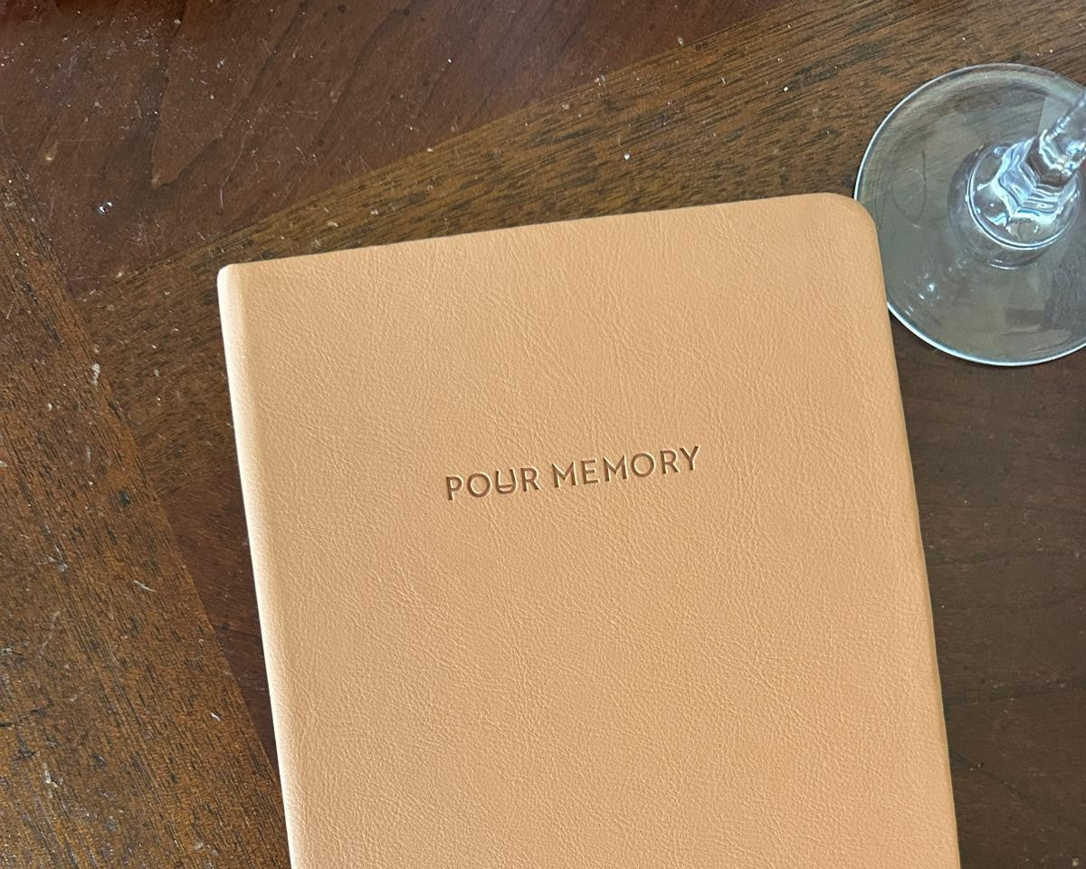 Vegan leather Pour Memory journal with wine glass on wooden table